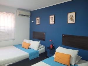 Costana - Hostal في كارتاهينا دي اندياس: غرفة بسريرين وجدار ازرق