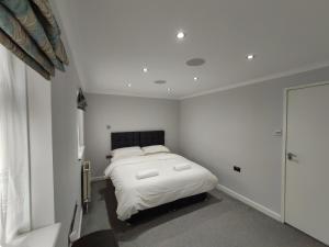 sypialnia z łóżkiem w białym pokoju w obiekcie Elegant 3-Bedroom Home, sleeps up to 5 guest. w mieście South Ockendon