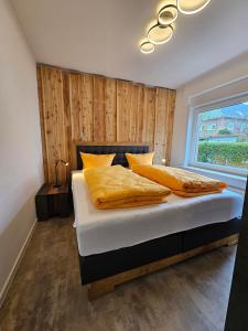 Un dormitorio con una cama con almohadas amarillas y una ventana en Ferienhaus Flechtner, en Norderney