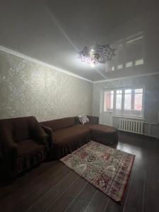 uma sala de estar com um sofá e um tapete em Квартира em Shymkent