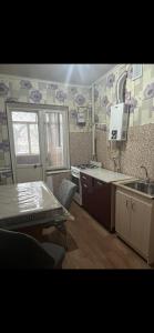una cocina con mesa, fregadero, mesa y mesa en Квартира, en Shymkent