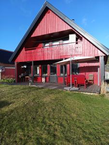 un granero rojo con dos bancos rojos en una cubierta en Villaidyll i Svanesund nära havet, en Svanesund