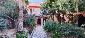 a house with palm trees and a walkway at Lac et Désert Agafay Tiki House chez Paul in Lalla Takerkoust