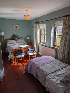 a bedroom with two beds and two chairs and windows at Drummonds House in Sligo