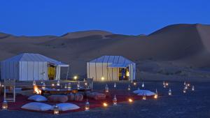 Merzouga Stars Luxury Camp في مرزوقة: مجموعة من الخيام في الصحراء في الليل