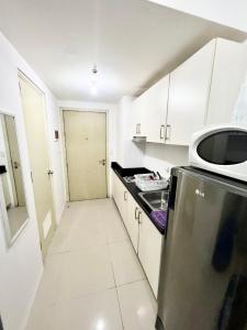 a white kitchen with a refrigerator and a microwave at Cozy Studio with SM Jazz Mall "12 floor" in Manila