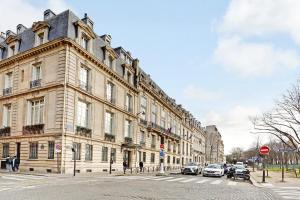 een groot gebouw met auto's geparkeerd voor het bij Pick A Flat's Apartment in Invalides - Rue de Constantine in Parijs