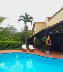 una piscina con 2 sillas y una casa en Finca PANACA Jagüey 12 VIP Group - Villas for Rent in, en Quimbaya