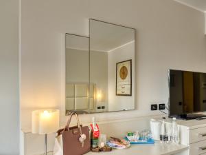 W łazience znajduje się umywalka i lustro. w obiekcie Parc Hotel w mieście Peschiera del Garda