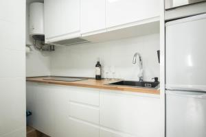 a white kitchen with a sink and white cabinets at Ático en Calella a 7 minutos de la playa in Calella