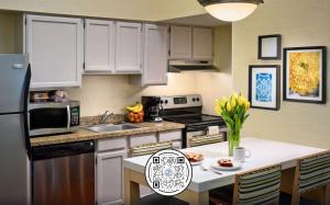 a kitchen with white cabinets and a table with flowers at Sonesta Simply Suites Memphis East Poplar Pike in Memphis