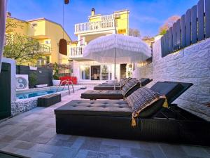 eine Terrasse mit 4 Betten mit einem Sonnenschirm und einem Pool in der Unterkunft Casa Memory in Crikvenica