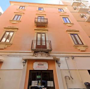 ein großes orangefarbenes Gebäude mit Fenstern und einem Balkon in der Unterkunft La Mattanza in Trapani