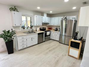 a kitchen with white cabinets and stainless steel appliances at Good Vibes House with private pool in Dania Beach