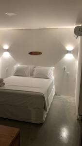 a bedroom with a large white bed with two lights at Dourados Villas Suites in São Miguel do Gostoso