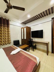 um quarto com uma cama, uma secretária e uma televisão em Hotel Satwah Home Stay em Nova Deli