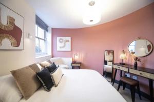 Schlafzimmer mit einem weißen Bett und einem Spiegel in der Unterkunft Bright and Spacious - 2 Bed Flat w/ Jacuzzi in Crystal Palace