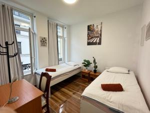 een slaapkamer met 2 bedden, een bureau en een raam bij Sweet Dream House in Brussel