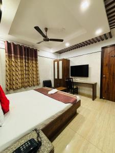 um quarto com uma cama, uma secretária e uma televisão em Hotel Satwah Home Stay em Nova Deli