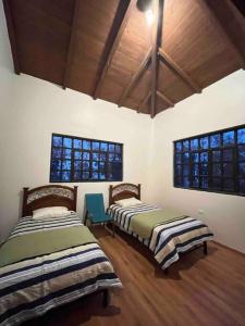 two beds in a room with two windows at Casa de campo - Fundo El Alisal in Cajamarca