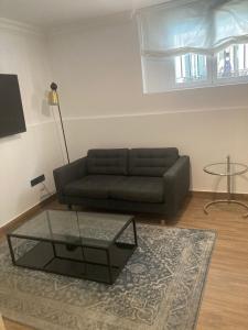 a living room with a couch and a glass coffee table at Alojamientos con encanto a orillas del Manzanares in Madrid