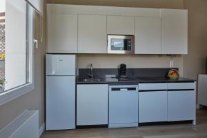 cocina con armarios blancos, fregadero y microondas en Apartamentos Cuerda Larga, en Madrid