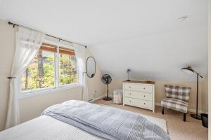 a bedroom with a bed and a window and a chair at Leisure Chalet close to Lake, Gunstock, Bank of New Hampshire Pavilion. in Gilford