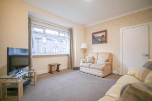 a living room with a couch and a tv at Lochlash 3 Bedroom House Inverness in Inverness