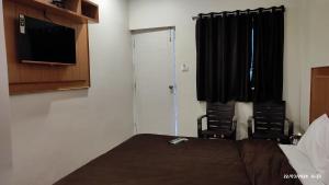 科代卡纳尔Magizham Homestay的一间卧室，有一张床、两把椅子和一台电视