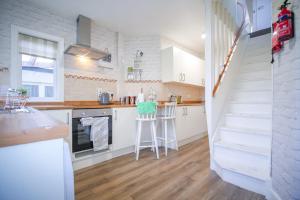 uma cozinha com armários brancos e uma escadaria em Lochlash 3 Bedroom House Inverness em Inverness