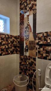 a bathroom with a toilet and a wall with tiles at Magizham Homestay in Kodaikānāl