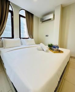 een groot wit bed in een kamer met ramen bij Swing & Pillows - KL Masjid India formerly known as Mountbatten Hotel Kuala Lumpur in Kuala Lumpur