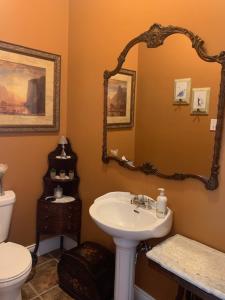 a bathroom with a sink and a toilet and a mirror at Gîte au Charme Victorien in Beauceville +18 photos