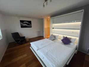 1 dormitorio con 1 cama blanca y 1 silla en Luxusferienhaus Isernhagen, en Altwarmbüchen
