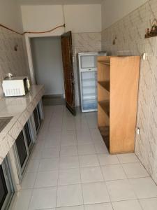 a kitchen with a refrigerator and a tiled floor at Appartement chambre meublée 1 in Dakar