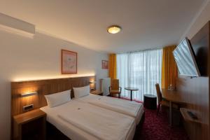 ノイシュタット・アン・デア・ヴァインシュトラーセにあるPanorama Hotel am Rosengartenのベッドとデスクが備わるホテルルームです。