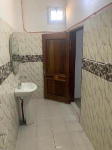 a bathroom with a sink and a wooden door at Appartement chambre meublée 1 in Dakar