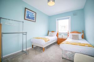 a blue room with two beds and a window at Telford St 4 Bedroom House Inverness in Inverness