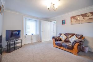 ein Wohnzimmer mit einem Sofa und einem TV in der Unterkunft Novar 4 Bedroom House Alness in Inverness