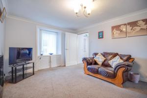 a living room with a couch and a television at Novar 4 Bedroom House Alness in Inverness