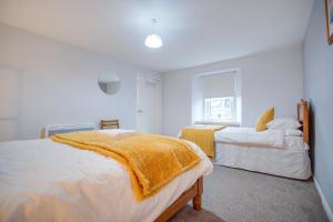 a white bedroom with two beds and a window at Novar 4 Bedroom House Alness in Inverness