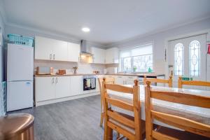 a kitchen with white cabinets and a table and chairs at Novar 4 Bedroom House Alness in Inverness