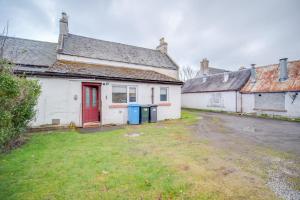 an old house with a red door in a yard at Novar 4 Bedroom House Alness in Inverness