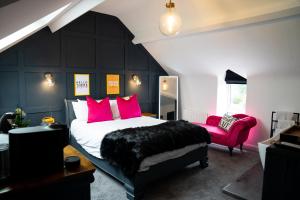 a bedroom with a large bed and a red chair at The Briers Country House in Newcastle