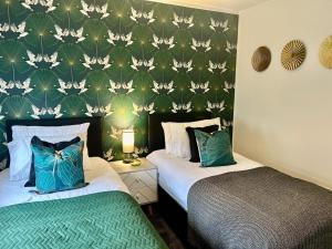 two beds in a bedroom with a green wall at Aitkenhead house by Klass Living in Coatbridge