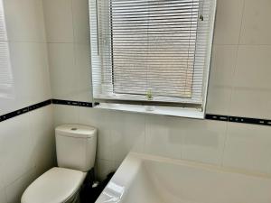 a bathroom with a toilet and a tub and a window at Aitkenhead house by Klass Living in Coatbridge