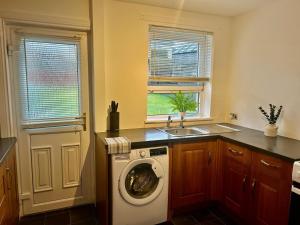 a kitchen with a washing machine and a sink at Aitkenhead house by Klass Living in Coatbridge