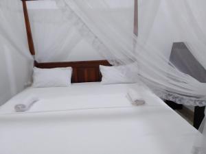 - 2 lits dans une chambre avec des rideaux blancs dans l'établissement Saimon Villa, à Mirissa