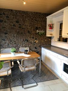 a kitchen with a table and chairs and a stone wall at Wohnung in Wald- und Seenähe in Erkner