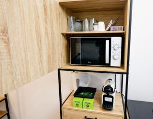 a microwave sitting on top of a shelf at Le Cocon - T2 Neuf avec Parking - Proche Hypercentre & Disneyland in Lagny